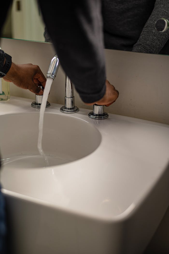 Crafting Captivating Headlines: Your awesome post title goes here Close-up of hands adjusting water flow in a modern ceramic sink with stainless faucet.