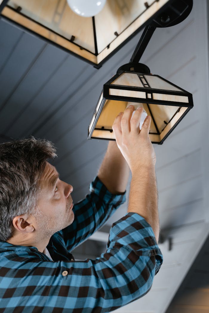 The Art of Drawing Readers In: Your attractive post title goes here Man in plaid shirt fixing a pendant light indoors.